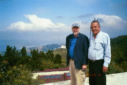 Bill Young and Philippe Villedrouin standing on a hill in Haiti with the ocean in the background.
