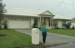 Picture of lady standing next to mailbox in front of a house.